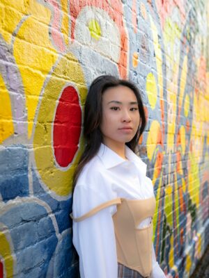 Stylish woman in urban fashion poses by a vibrant graffiti wall.