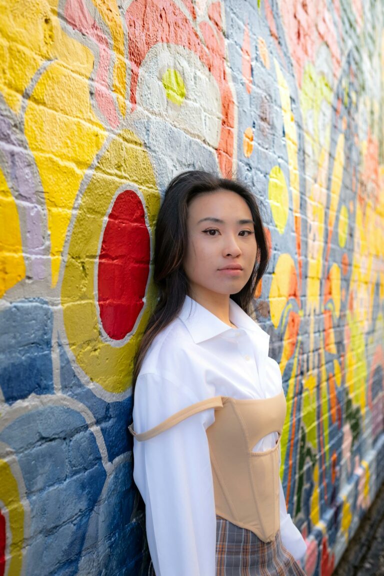 Stylish woman in urban fashion poses by a vibrant graffiti wall.