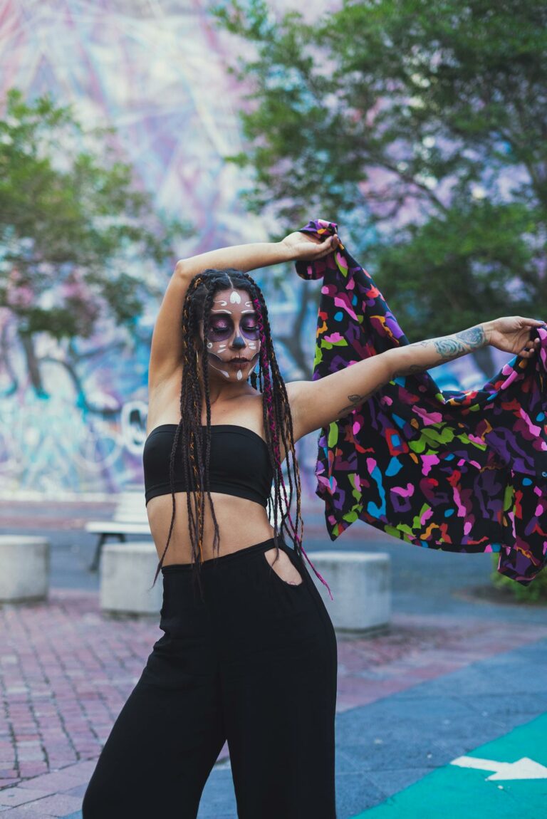 Woman expressing freedom with colorful scarf and face paint in urban setting.
